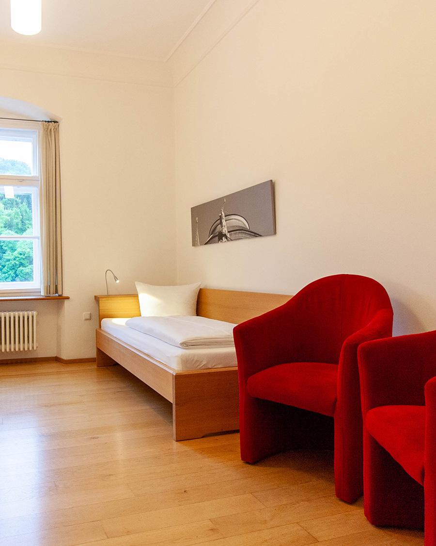 Zimmer mit zwei Einzelbetten und zwei roten Hockern im Gästehaus St.Georg