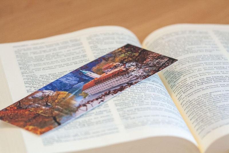 Lesezeichen mit Motiv des Klosters Weltenburg in einem aufgeschlagenen Buch.