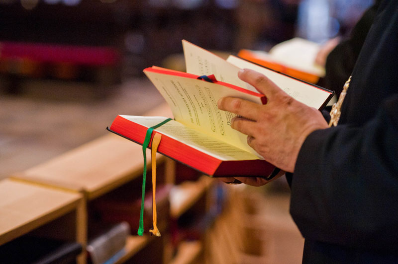 Person blättert in einem liturgischen Buch während eines Gottesdienstes in einer Kirche