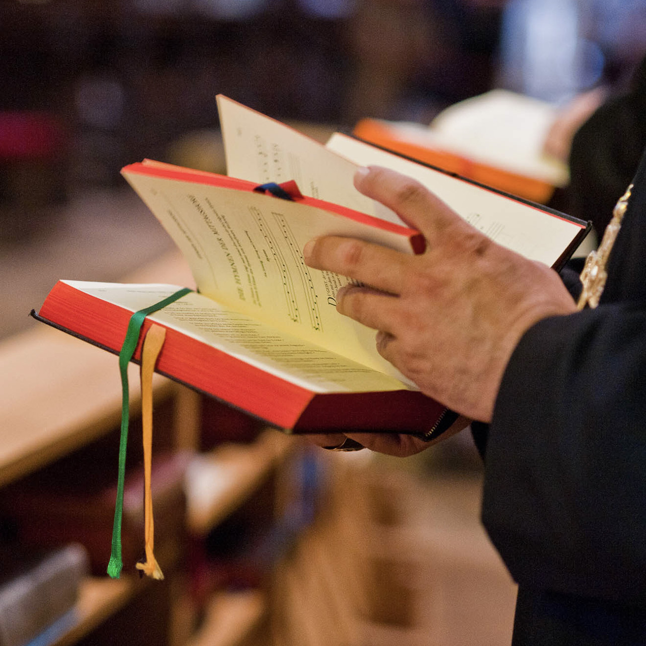 Person blättert in einem liturgischen Buch während eines Gottesdienstes in einer Kirche.
