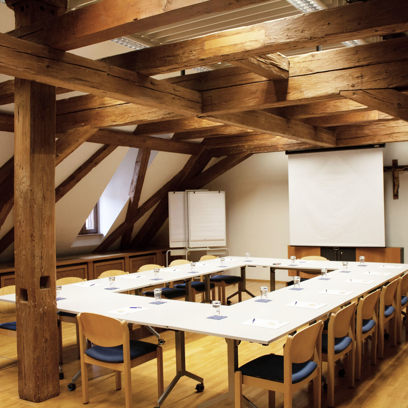 Tagungsraum mit angeordneten Tischen, Stühlen und Schreibunterlagen im Gästehaus St. Georg