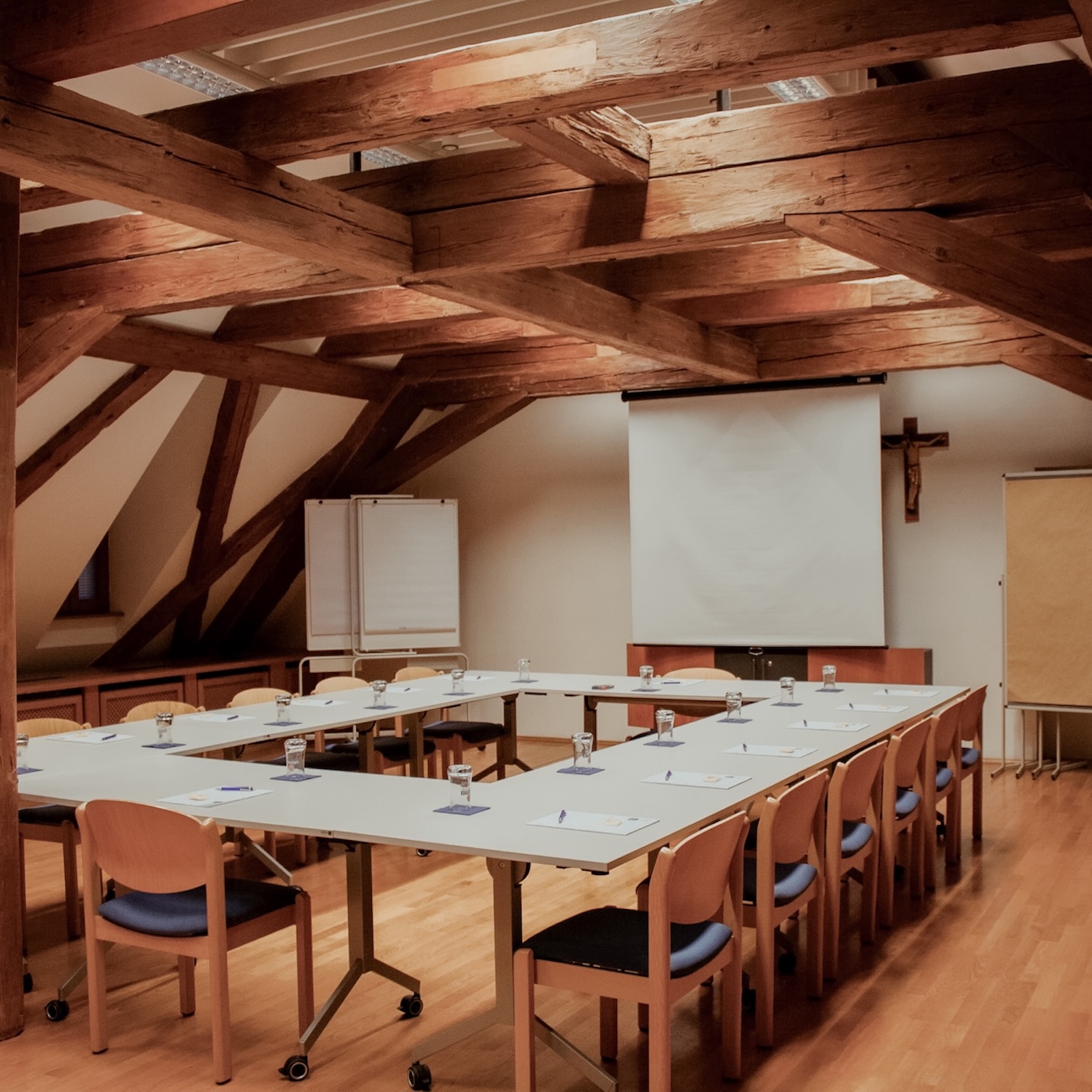 Tagungsraum mit angeordneten Tischen, Stühlen und Schreibunterlagen im Gästehaus St. Georg