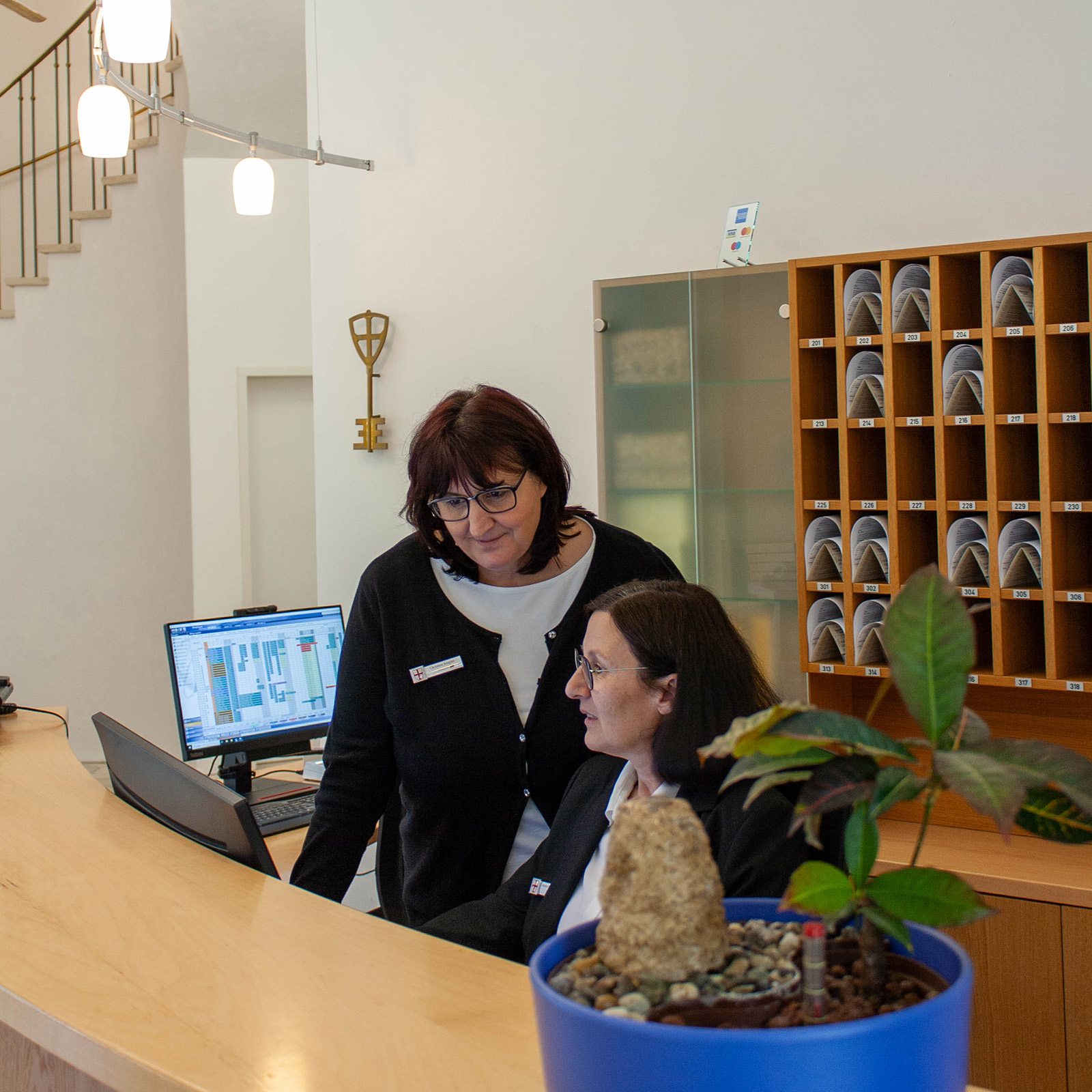 Rezeption mit zwei Mitarbeiterinnen am Computer vor Schlüsselwand in Gästehaus St.Georg