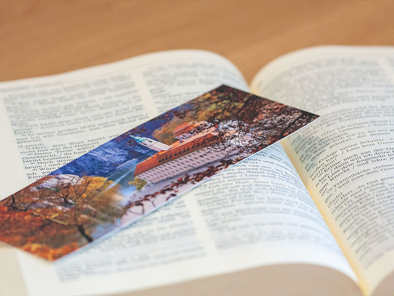 Lesezeichen mit Motiv des Klosters Weltenburg in einem aufgeschlagenen Buch.