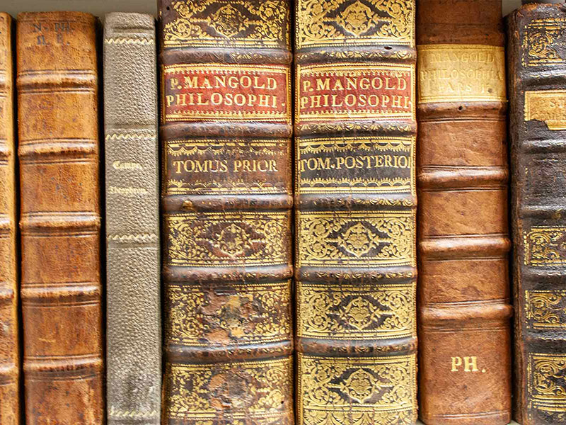 Historische Bücher mit verzierten Ledereinbänden in einer Klosterbibliothek.