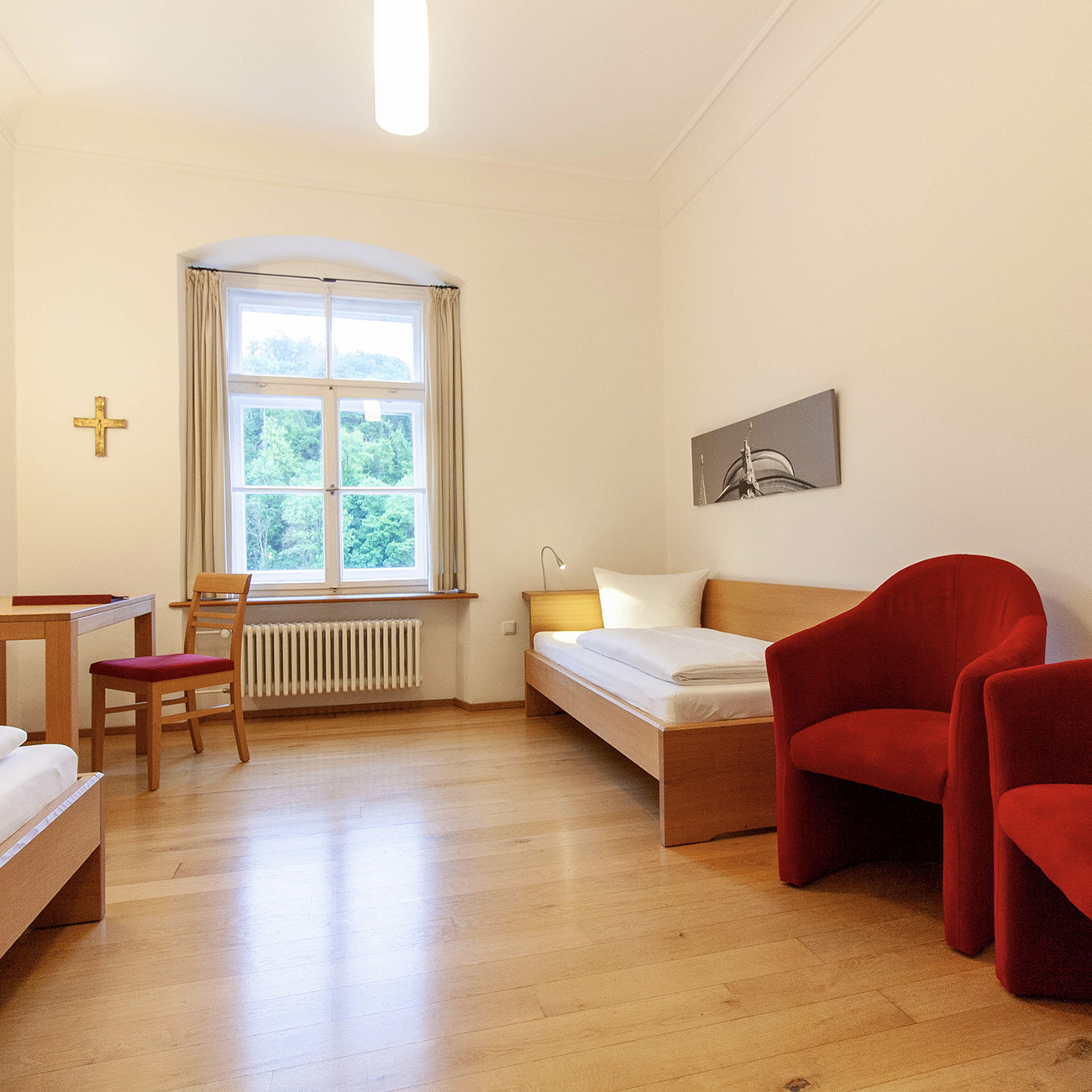Zimmer mit zwei Einzelbetten und zwei roten Hockern im Gästehaus St.Georg